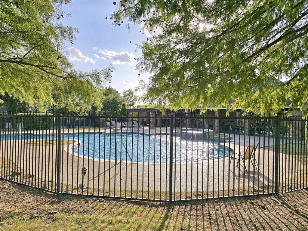 1504 Fox Run Drive, Irving, TX 75063 Swimming pool featuring a concrete surround, elevated spa, wrought-iron perimeter fencing, and an expansive covered pavilion
