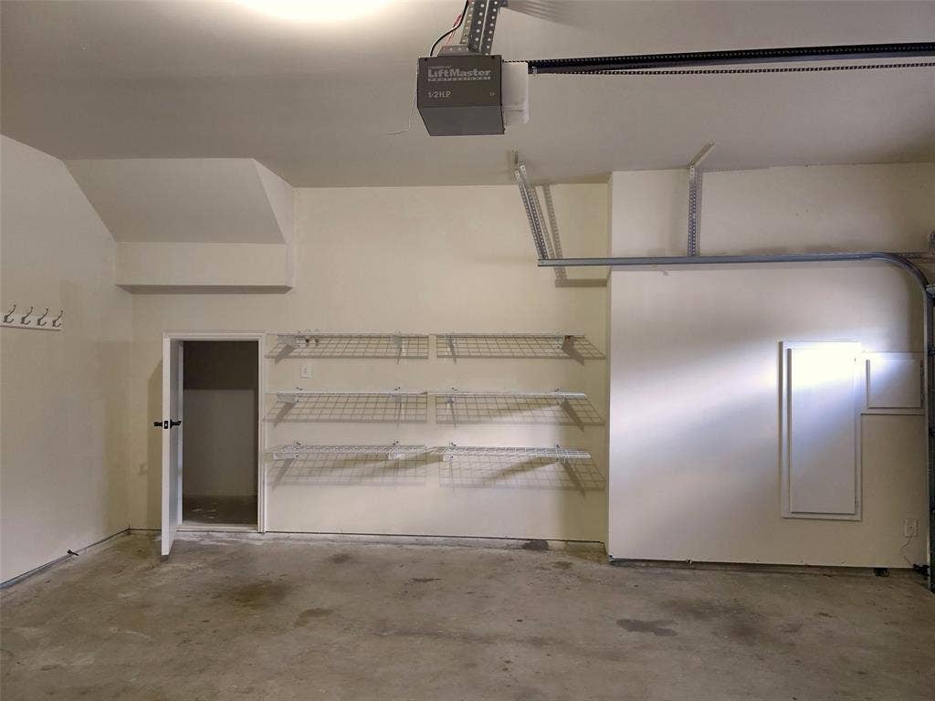 1504 Fox Run Drive, Irving, TX 75063 Garage featuring a concrete floor, motorized door opener, wall-mounted wire shelving, and built-in storage panels