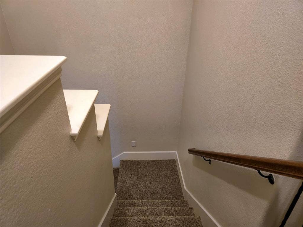 1504 Fox Run Drive, Irving, TX 75063 Staircase featuring neutral-toned carpeting, painted wall caps, and a wall-mounted wooden handrail with metal hardware