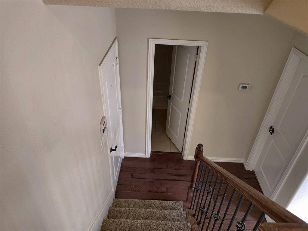 1504 Fox Run Drive, Irving, TX 75063 Staircase featuring a wooden handrail with metal balusters, carpeted steps, wood-finish flooring, and white paneled doors
