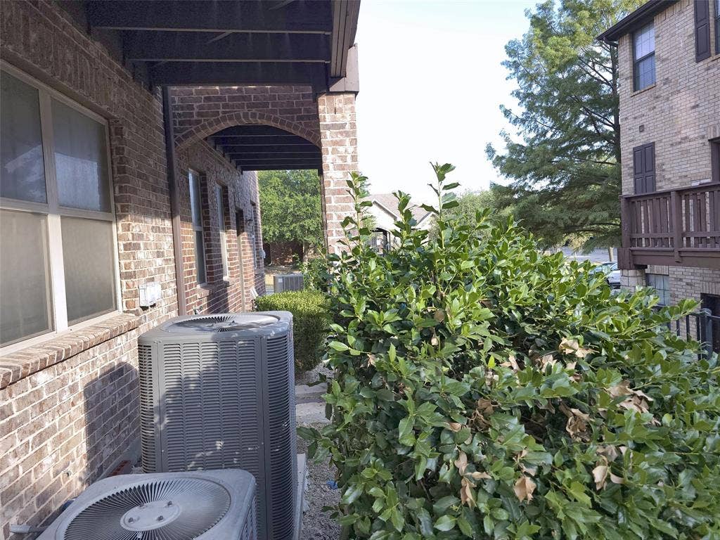 1504 Fox Run Drive, Irving, TX 75063 Exterior brick facade featuring arched architectural detailing, covered outdoor structure, and mature landscaping