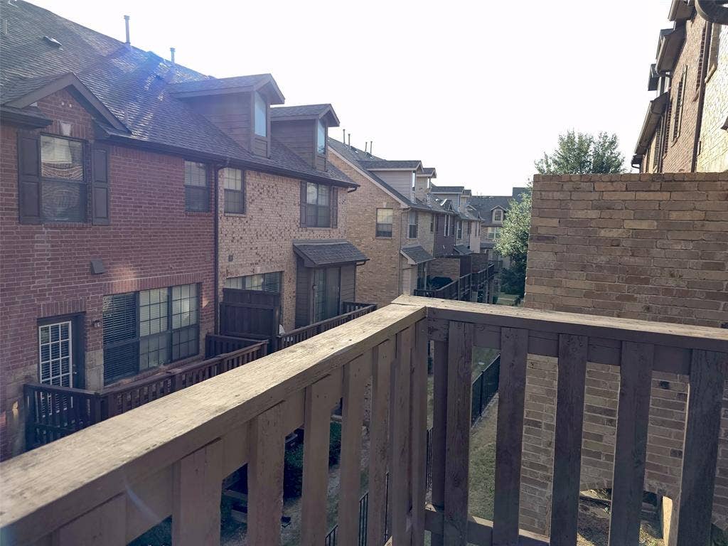 1504 Fox Run Drive, Irving, TX 75063 Elevated deck with wooden railings, multi-story brick exterior, and roof dormers