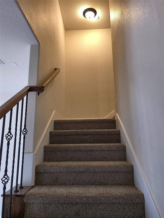 1504 Fox Run Drive, Irving, TX 75063 Staircase featuring wall-to-wall carpeting, wood handrail, decorative metal balusters, and a flush-mount ceiling light fixture