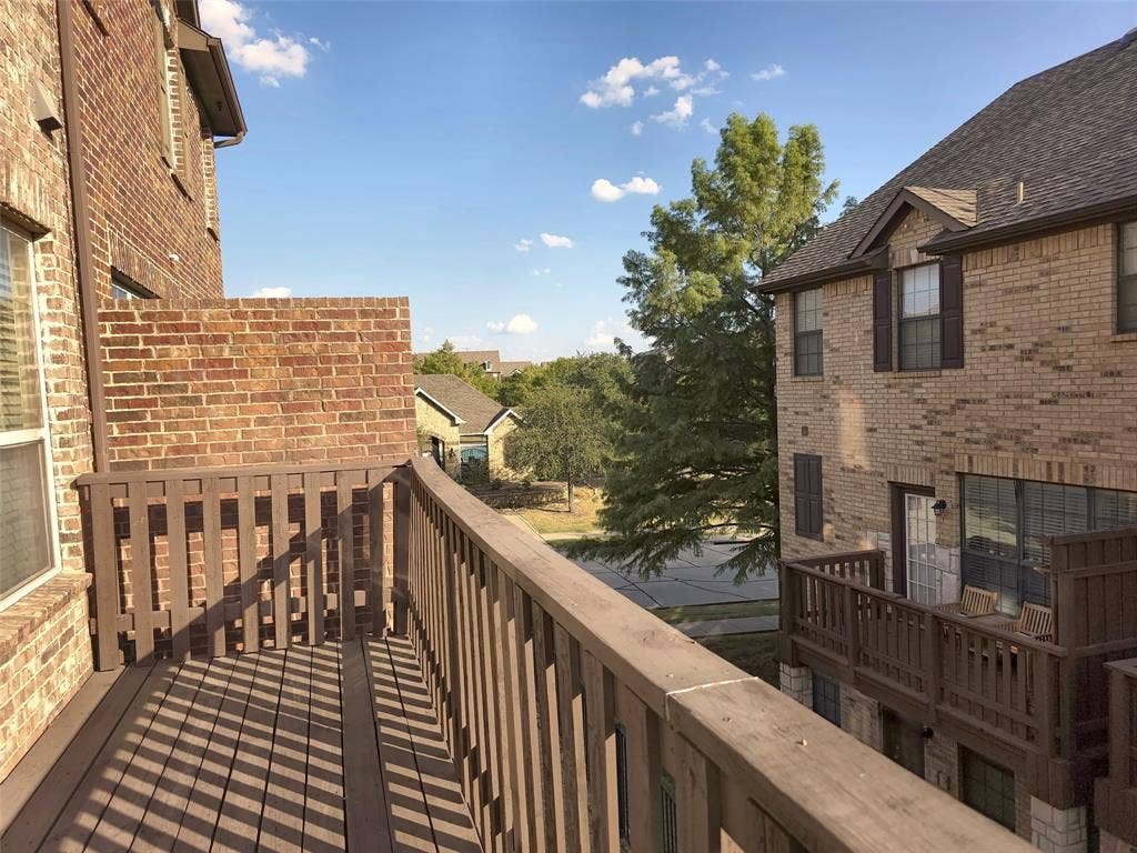 1504 Fox Run Drive, Irving, TX 75063 Second-level elevated deck featuring wood-tone railings, composite plank flooring, and a partial brick privacy wall