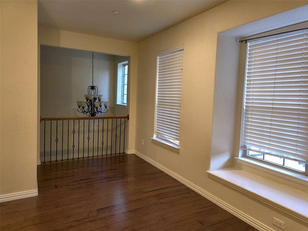 1504 Fox Run Drive, Irving, TX 75063 Wood-finish flooring, two deep-sill windows with built-in bench seating, wrought iron balusters, and a tiered decorative chandelier