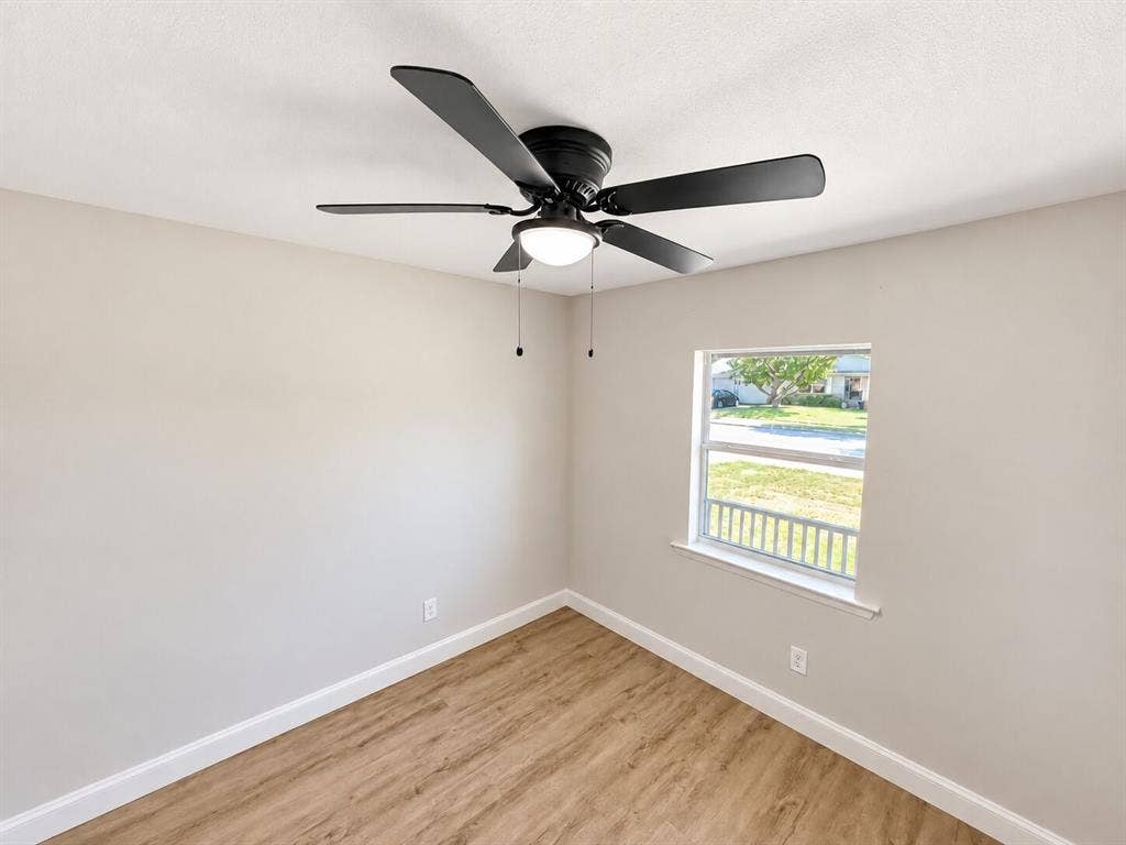 1307 Crestridge Drive, Plano, TX 75075 Neutral wall finish, wood-finish flooring, and black matte five-blade ceiling fan with integrated dome lighting and single-pane window