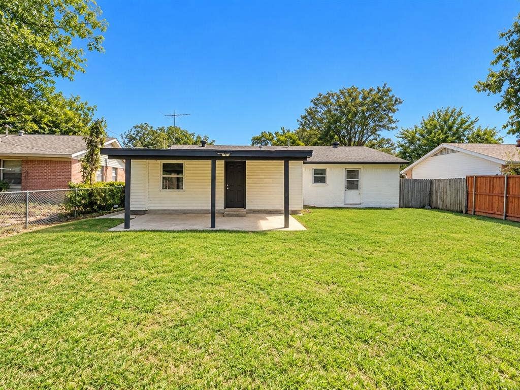 1307 Crestridge Drive, Plano, TX 75075 Rear exterior featuring a covered concrete patio, light-colored siding, and a fenced backyard with lawn