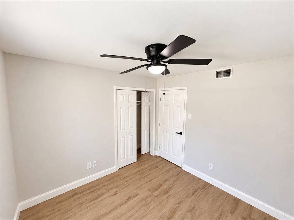 1307 Crestridge Drive, Plano, TX 75075 Room featuring wood-finish flooring, a matte black ceiling fan with an integrated light fixture, and six-panel interior doors