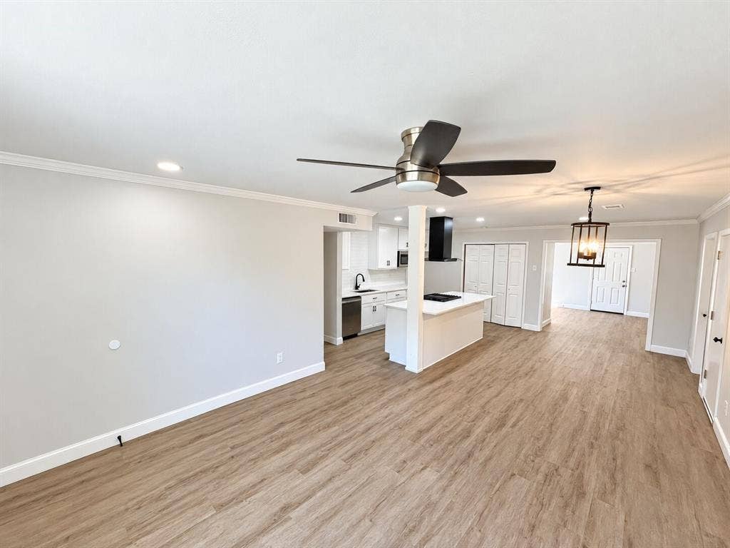 1307 Crestridge Drive, Plano, TX 75075 Open-concept interior featuring wood-finish flooring, a kitchen island with stone-finish countertops, recessed lighting, a modern metal-frame pendant light, and a ceiling fan