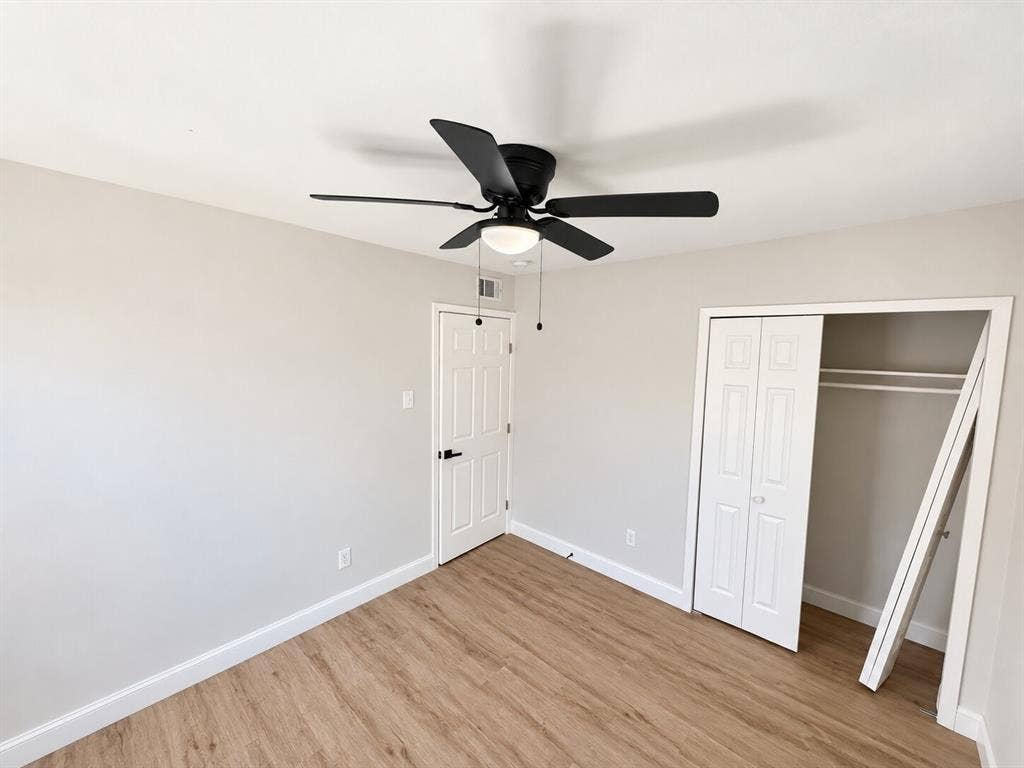 1307 Crestridge Drive, Plano, TX 75075 Interior room featuring wood-finish flooring, a ceiling fan with integrated light fixture, a paneled interior door with matte black hardware, and a closet with bifold doors