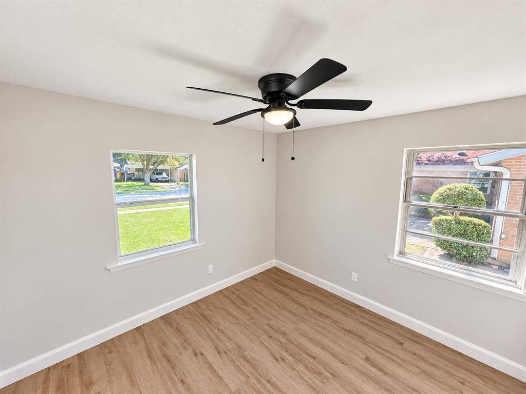 1307 Crestridge Drive, Plano, TX 75075 Interior space featuring wood-finish flooring, neutral wall paint, two dual-pane windows, and a matte black ceiling fan with integrated lighting