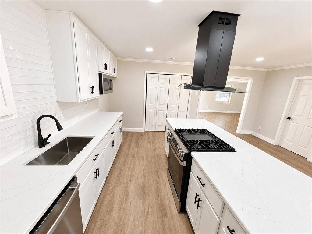 1307 Crestridge Drive, Plano, TX 75075 Kitchen featuring white cabinetry, solid-surface countertops, a center island with an integrated gas cooktop, a stainless steel range, and a ceiling-mounted range hood