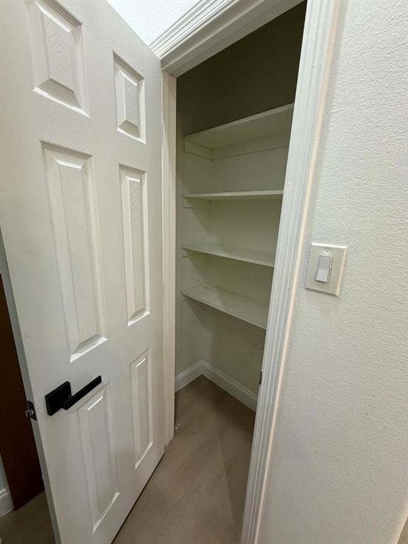 5864 Oram Street, Dallas, TX 75206 Pantry featuring a six-panel door with matte black hardware and three levels of fixed shelving