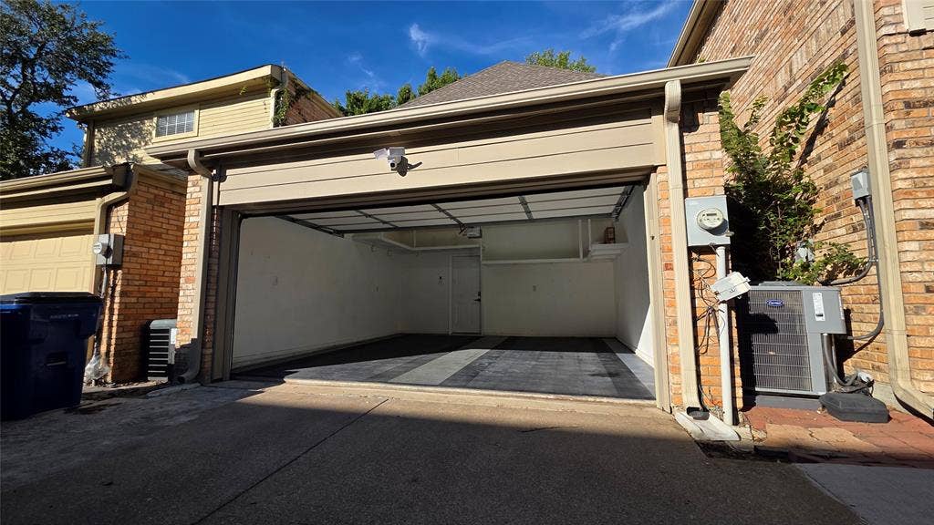 5864 Oram Street, Dallas, TX 75206 Attached two-car garage featuring segmented flooring, high-contrast wall finishes, and overhead lighting