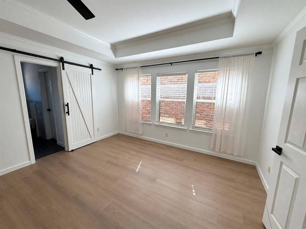 5864 Oram Street, Dallas, TX 75206 Tray ceiling with recessed lighting, wood-finish flooring, sliding white barn door with matte black hardware, and three-pane window configuration