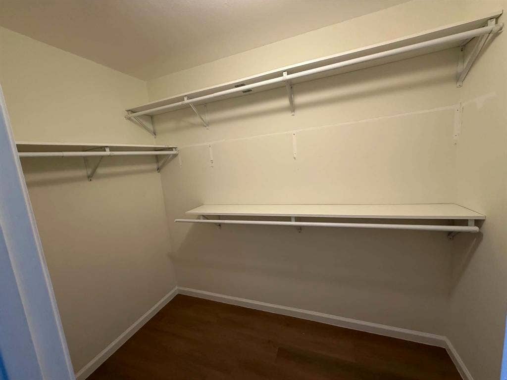 5864 Oram Street, Dallas, TX 75206 Primary Walk-in closet featuring wood-finish flooring and multi-level white built-in shelving with integrated clothing rods