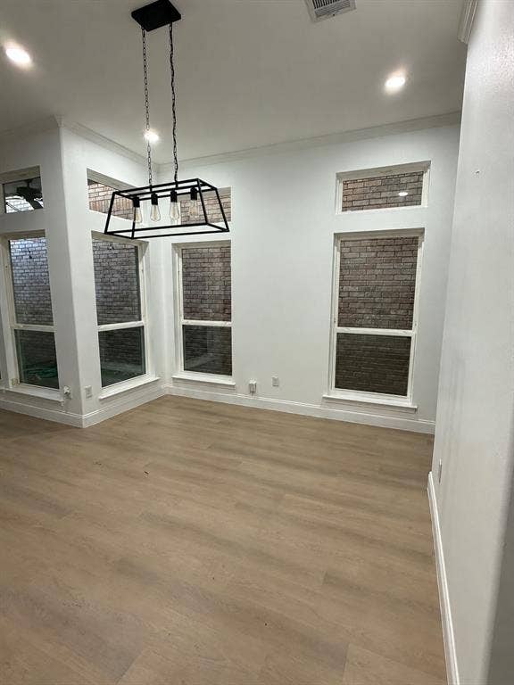 5864 Oram Street, Dallas, TX 75206 Open-concept space featuring wood-finish flooring, rectangular windows with brick exterior detailing, recessed lighting, and a linear pendant fixture with a matte black frame