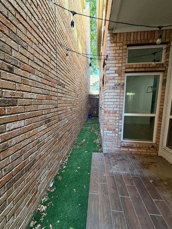 5864 Oram Street, Dallas, TX 75206 Exterior space featuring brick siding, a paved patio with wood-finish tile, and a synthetic turf side yard
