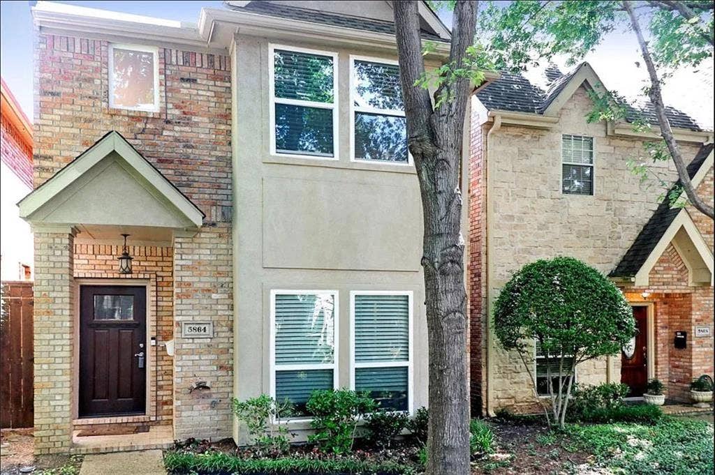 5864 Oram Street, Dallas, TX 75206 Two-story exterior featuring a mix of brick and stucco siding, a covered entryway with a gabled roofline, dark-finish wooden front door, and multi-pane windows