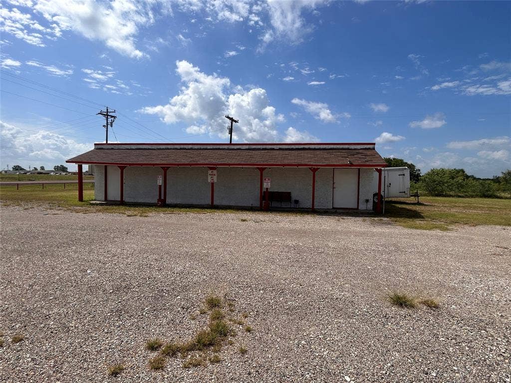 8440 E Highway 175 Highway, Kemp, TX 75143 Single-story structure featuring a covered front porch, red-trimmed architectural accents, gravel lot, and multiple exterior access points