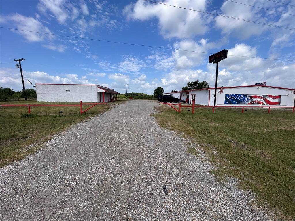 8440 E Highway 175 Highway, Kemp, TX 75143 Commercial property featuring two exterior structures, expansive gravel grounds, and red metal perimeter fencing