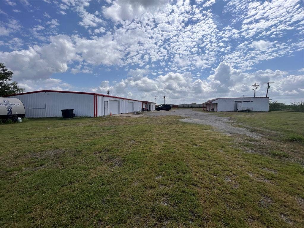 8440 E Highway 175 Highway, Kemp, TX 75143 Expansive lot featuring two metal-sided warehouse buildings, multiple roll-up garage doors, and a gravel parking area