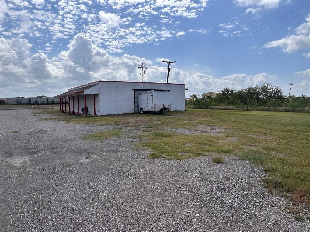 8440 E Highway 175 Highway, Kemp, TX 75143 Single-story structure featuring a concrete exterior, a covered side porch with support columns, and an expansive gravel lot