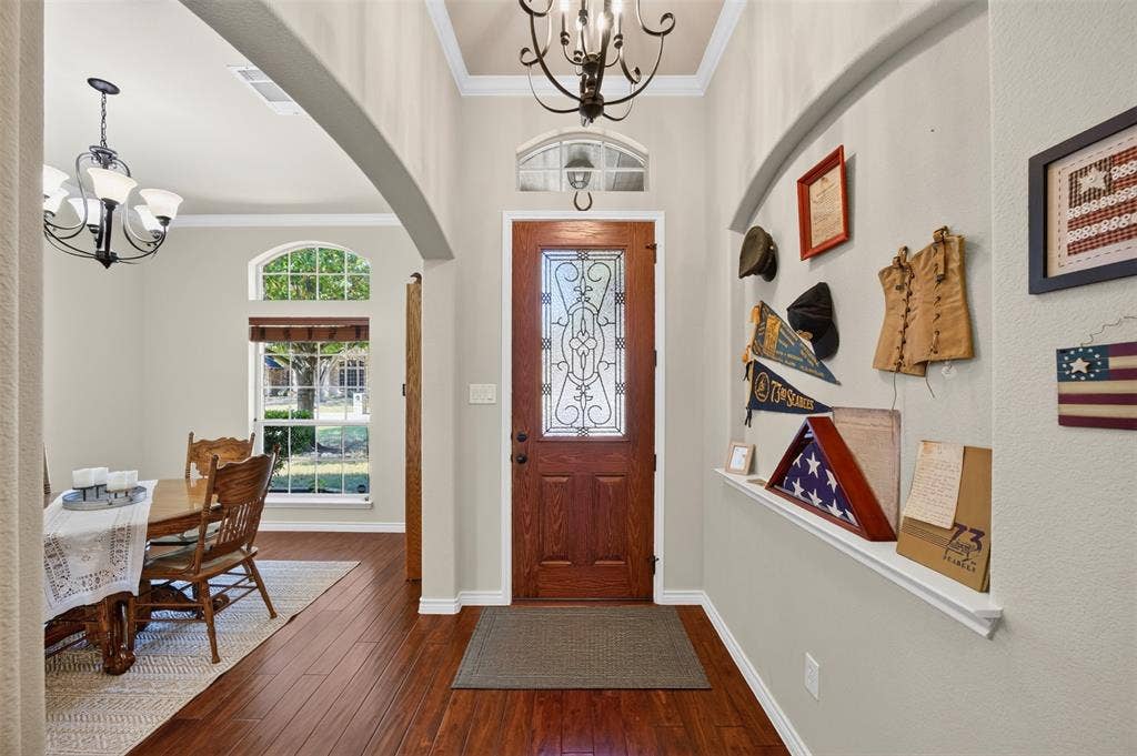 1514 Natalie Lane, Duncanville, TX 75137 Foyer featuring arched entryway, wood-finish flooring, recessed wall niche, and front door with decorative glass insert and transom window