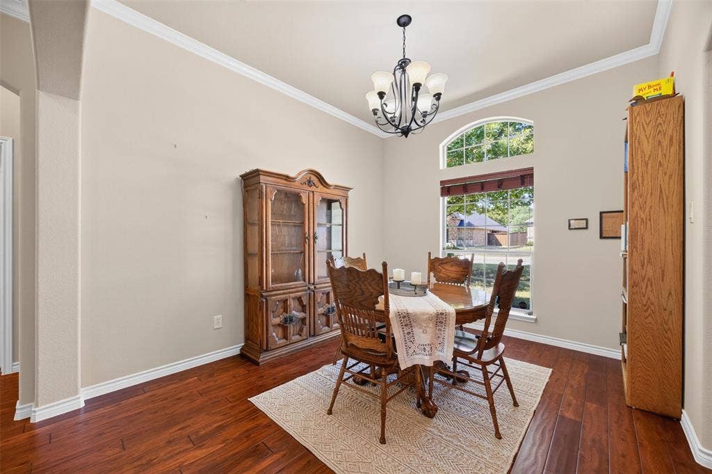 1514 Natalie Lane, Duncanville, TX 75137 Dining area featuring wood-finish flooring, an arched window, crown molding, and a tiered multi-light chandelier