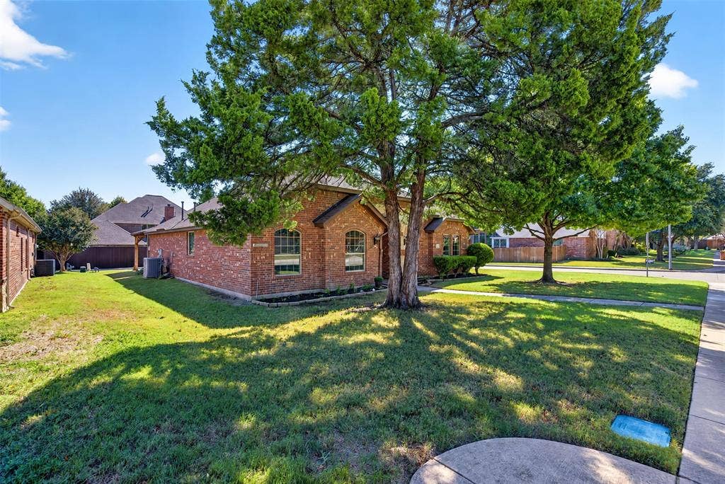 1514 Natalie Lane, Duncanville, TX 75137 Brick exterior featuring arched windows, mature canopy trees, and a manicured lawn