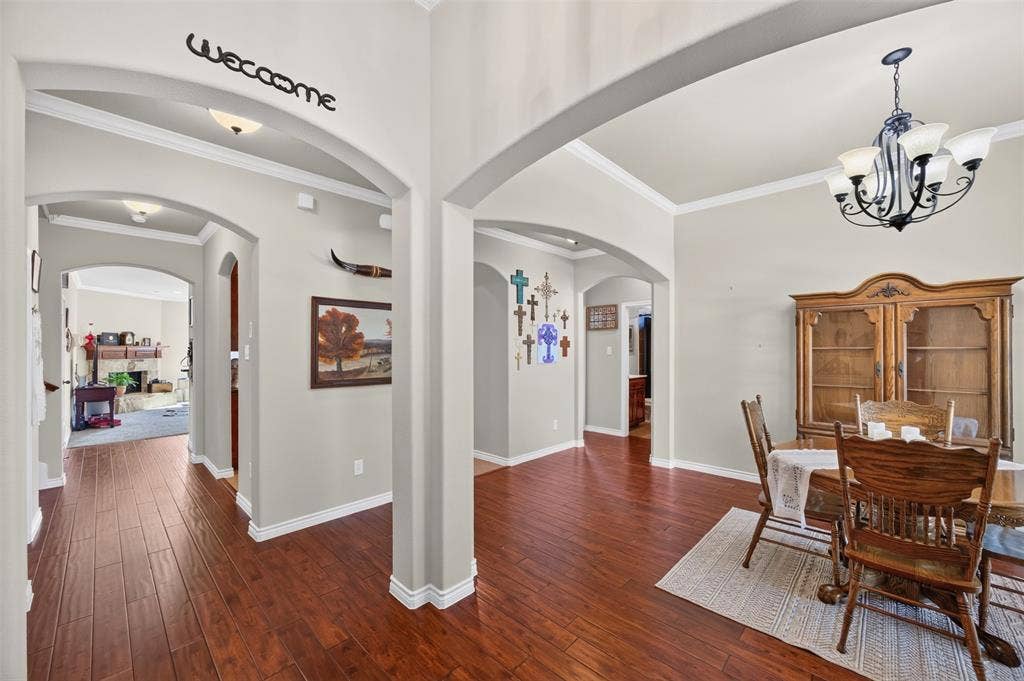 1514 Natalie Lane, Duncanville, TX 75137 Arched architectural detailing, wood-finish flooring, and crown molding throughout, illuminated by a multi-arm chandelier and recessed lighting