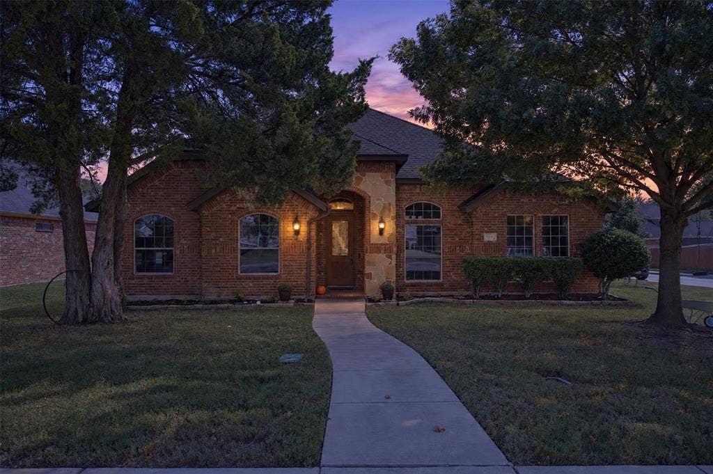 1514 Natalie Lane, Duncanville, TX 75137 Brick and stone facade featuring an arched entryway, stone detailing, arched windows, and a concrete walkway