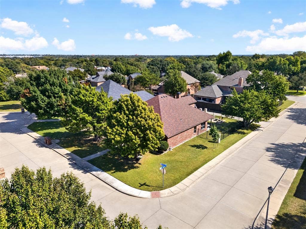 1514 Natalie Lane, Duncanville, TX 75137 Corner lot featuring a brick exterior, hipped roofline, mature trees, and concrete sidewalk infrastructure