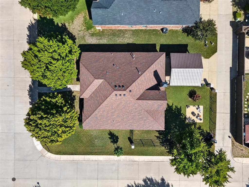 1514 Natalie Lane, Duncanville, TX 75137 Aerial view featuring a shingle roof, a detached metal-roofed structure, and mature trees on a corner lot