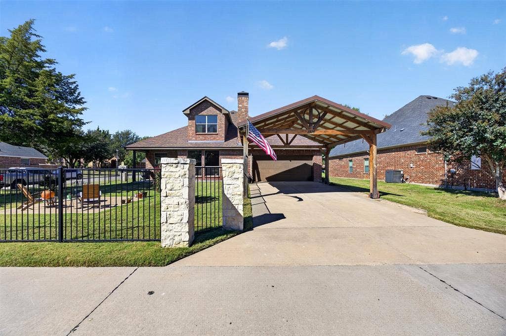 1514 Natalie Lane, Duncanville, TX 75137 Brick exterior featuring a detached timber-frame carport, stone-capped fencing, and concrete driveway