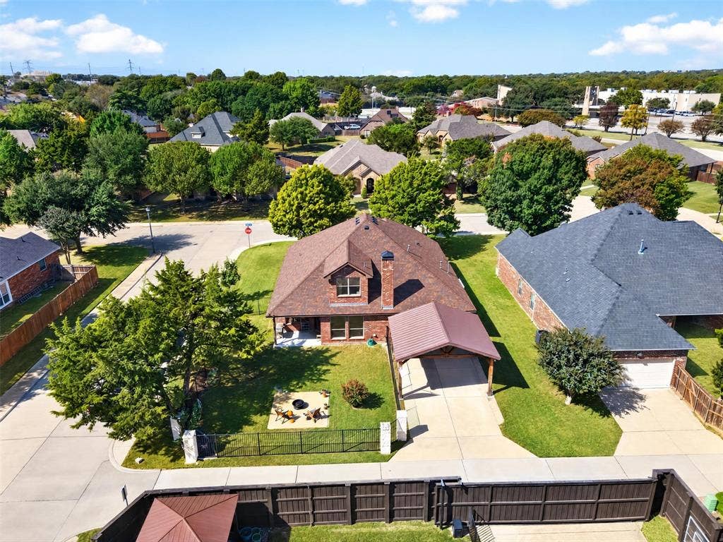 1514 Natalie Lane, Duncanville, TX 75137 Aerial view of brick exterior home featuring a steep-pitched roof, covered carport, dormer window, and fenced yard with a stone-surfaced patio area