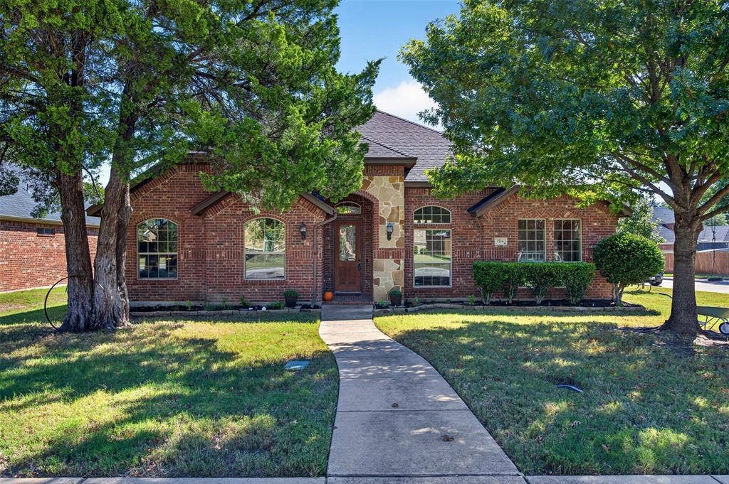 1514 Natalie Lane, Duncanville, TX 75137 Brick exterior featuring stone accents, arched window detailing, and a multi-gabled roofline