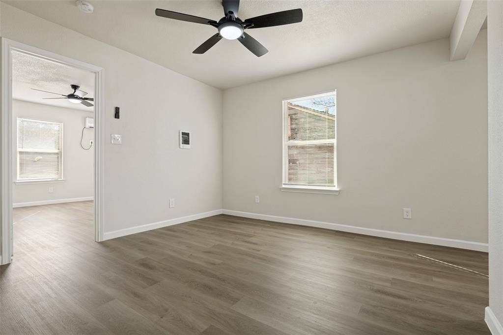 Neutral wall palette featuring wood-finish flooring, recessed windows, and a matte black ceiling fan with integrated lighting