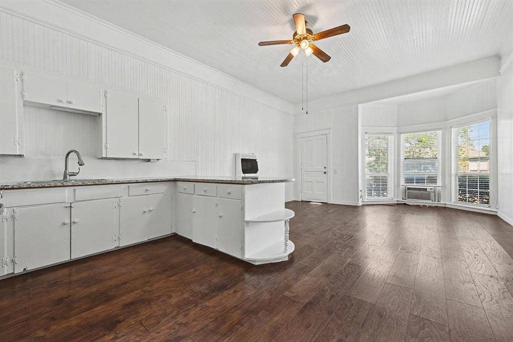 105 College Street, #107, Wylie, TX 75098 Kitchen featuring stone-finish countertops, wood-finish flooring, beadboard wall paneling, a vaulted ceiling, and a bay window