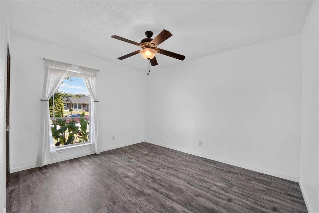 2130 Bowie Drive, Carrollton, TX 75006 Wood-finish flooring, central ceiling fan with integrated light fixture, and a large window featuring neutral walls