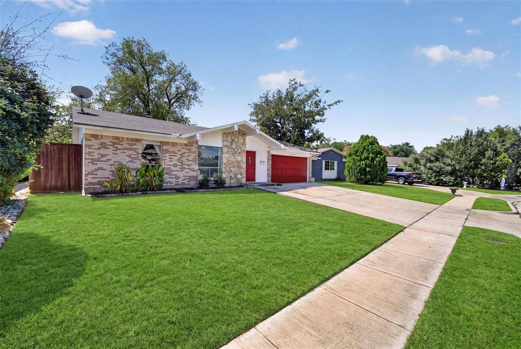 2130 Bowie Drive, Carrollton, TX 75006 Single-story exterior featuring multi-toned brick facade, natural stone accent wall, concrete driveway, and attached garage
