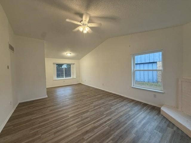 Interior space featuring vaulted ceilings, wood-finish flooring, a ceiling fan with light kit, double-pane windows, and a raised hearth fireplace
