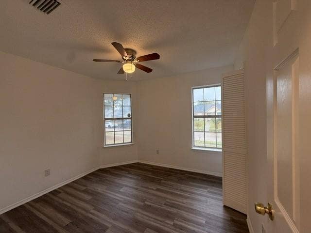 Room featuring wood-finish flooring, dual windows, ceiling fan with integrated lighting, and louvered closet doors