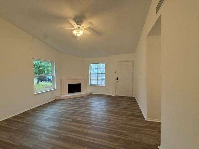 Vaulted ceilings, wood-finish flooring, corner fireplace with raised hearth, and multiple windows providing natural light