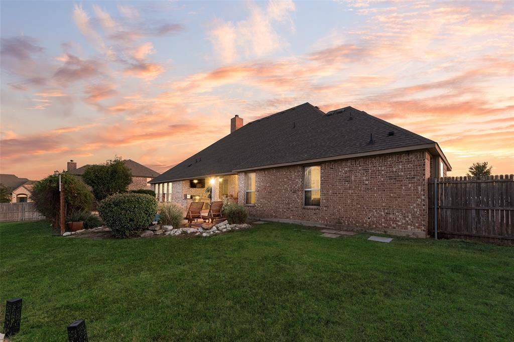 7231 Judy Drive, Ovilla, TX 75154 Brick exterior residence featuring a covered patio, rock-lined landscaping, a fenced backyard, and a shingle roof