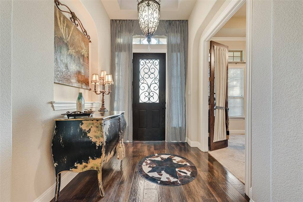 7231 Judy Drive, Ovilla, TX 75154 Foyer featuring wood-finish flooring, an arched entryway, recessed ceiling detailing, an ornate hanging pendant light, and a front door with decorative iron scrollwork