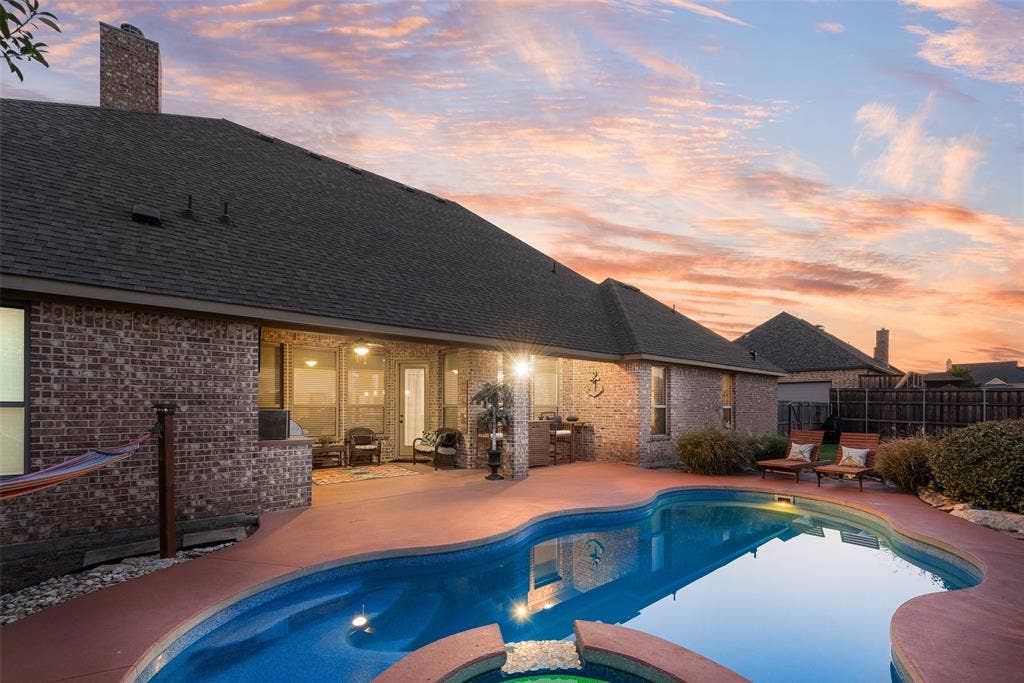 7231 Judy Drive, Ovilla, TX 75154 Brick exterior residence featuring a rear swimming pool with integrated spa, expansive stained concrete patio, and a covered outdoor living area