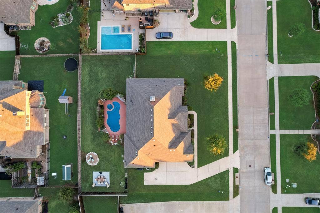 7231 Judy Drive, Ovilla, TX 75154 Aerial perspective of a property featuring an in-ground swimming pool with an integrated spa, expansive lawn, concrete driveway, and wood fencing