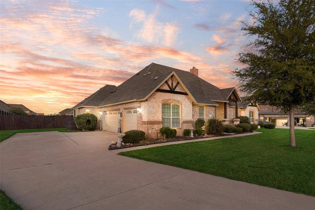 7231 Judy Drive, Ovilla, TX 75154 Single-story brick and stone veneer exterior featuring a multi-gable roofline, attached two-car garage, expansive concrete driveway, and manicured landscaping