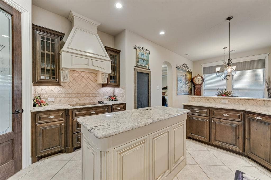 7231 Judy Drive, Ovilla, TX 75154 Kitchen featuring custom wood cabinetry, stone countertops, central island, tiled backsplash, and decorative range hood